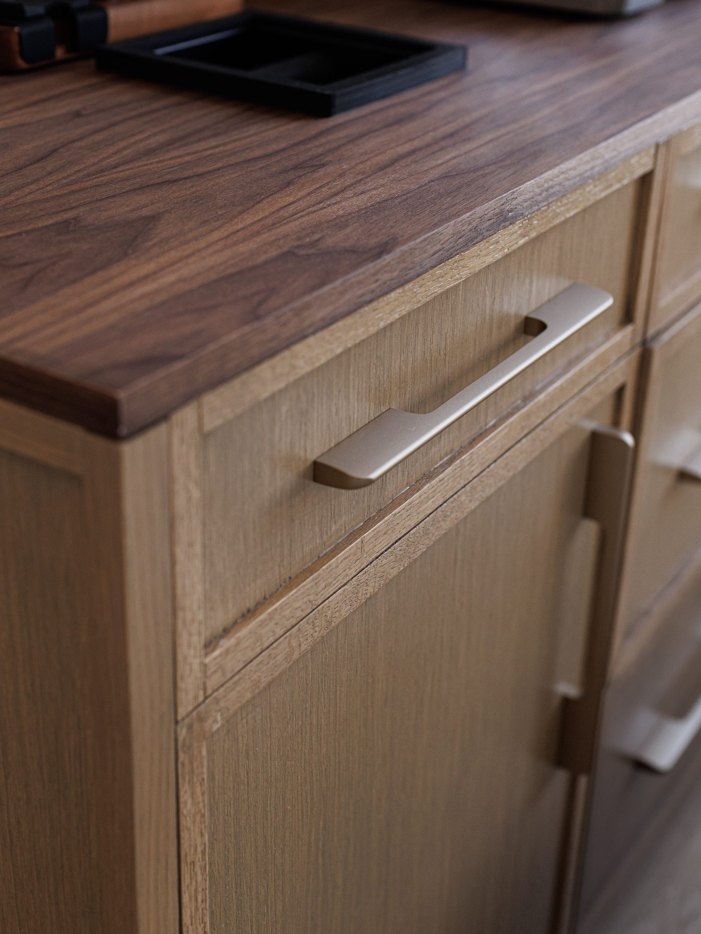 Macro of brass pull and walnut top edge